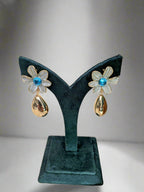AzurePetal Bloom Drops – pearlescent petal earrings with blue gem and gold-tone droplet charms