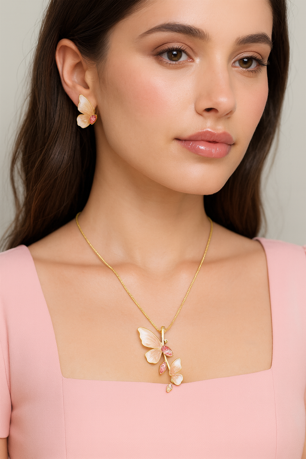 Woman wearing a gold necklace with a butterfly pendant and matching earrings.